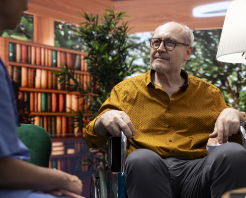 Care provider discussing specialist dementia training with an elderly man in a wheelchair and his supportive wife
