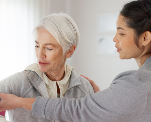 A carer gently assisting an older person, reflecting the hands-on support of middle stage dementia care