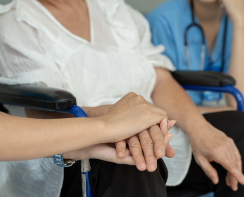 Caregiver supporting elderly patient in wheelchair, concept of resources for carers and senior care